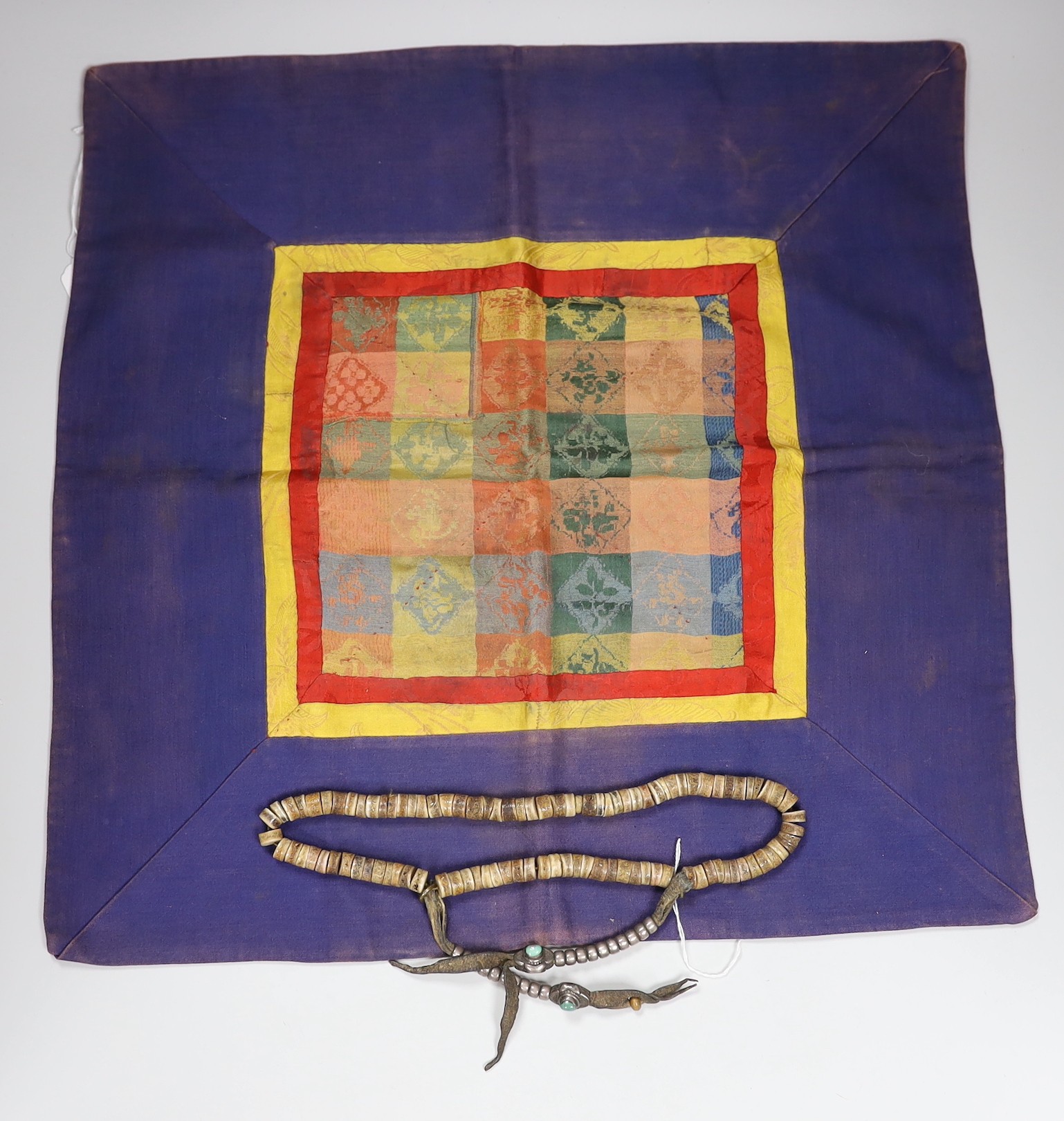 A Tibetan bone, coral and turquoise mounted necklace and a brocade mounted panel